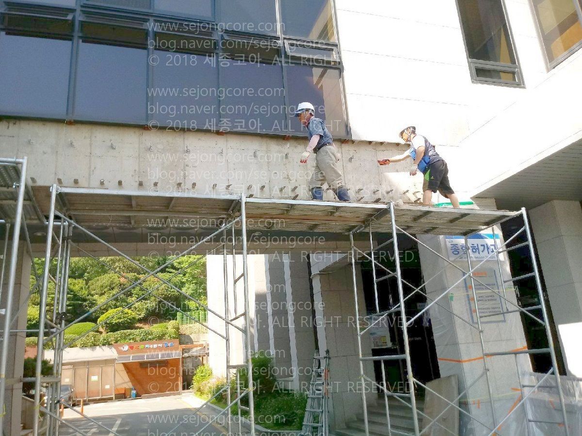 맑은 날. 김포 시청의 본관과 별관을 연결하는 다리 앞에 피티아시바를 둔 것이 보인다. 그 위에는 장경화와 다른 1명이 올라가 있다. 장경화는 거의 맨 오른쪽에서 컷팅 작업을 위한 먹줄(선)이 정확히 그어졌는지 확인하고 있다.